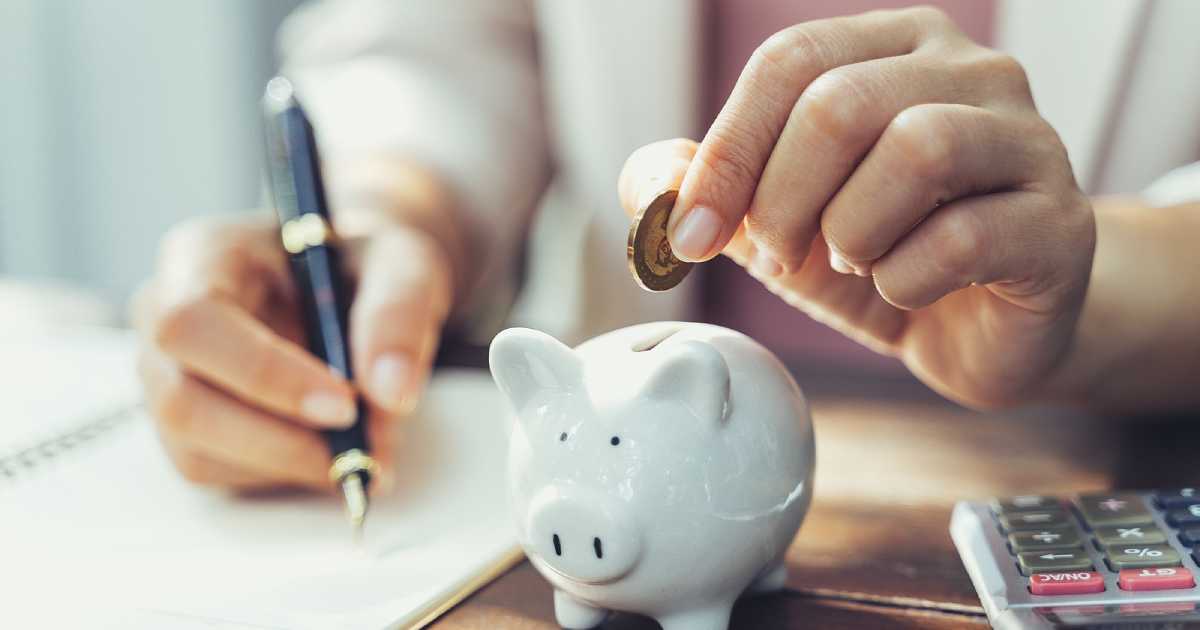 woman putting coin in piggy bank