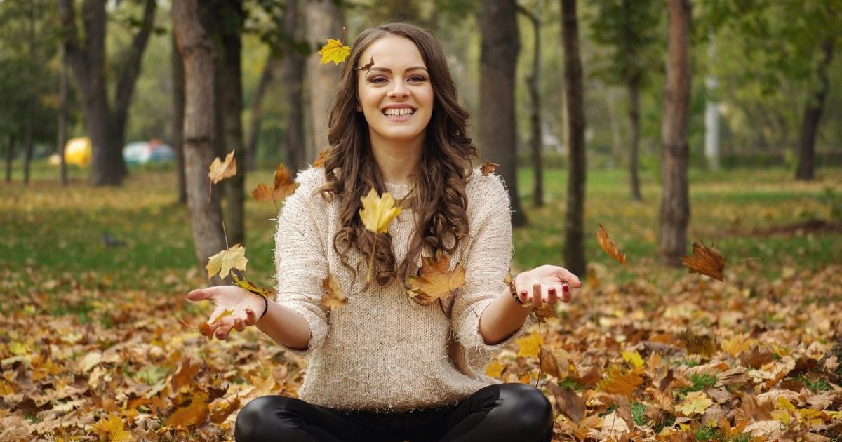 woman throwing autumn leaves in the air